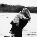 Black and white photo showing a mom lovingly holding her toddler against a scenic lake backdrop. Toddlers are tough, but they are also tender. We can help our children to not feel abandoned