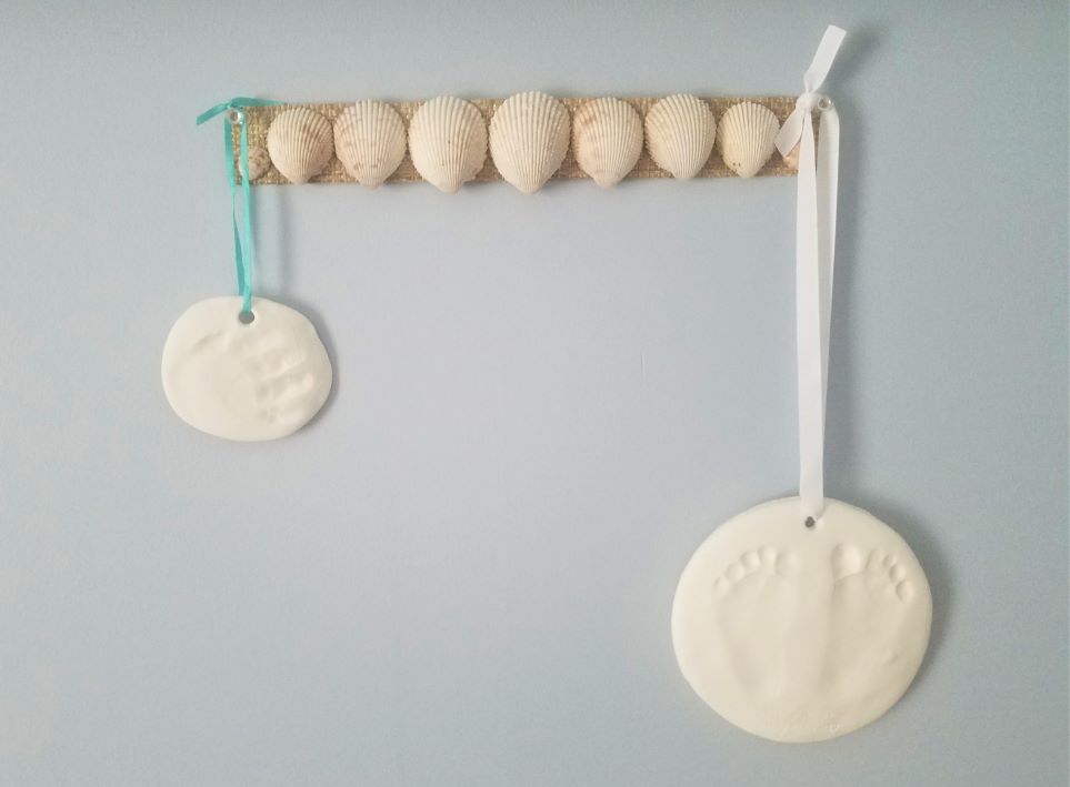 Shells on burlap with baby footprints and handprint