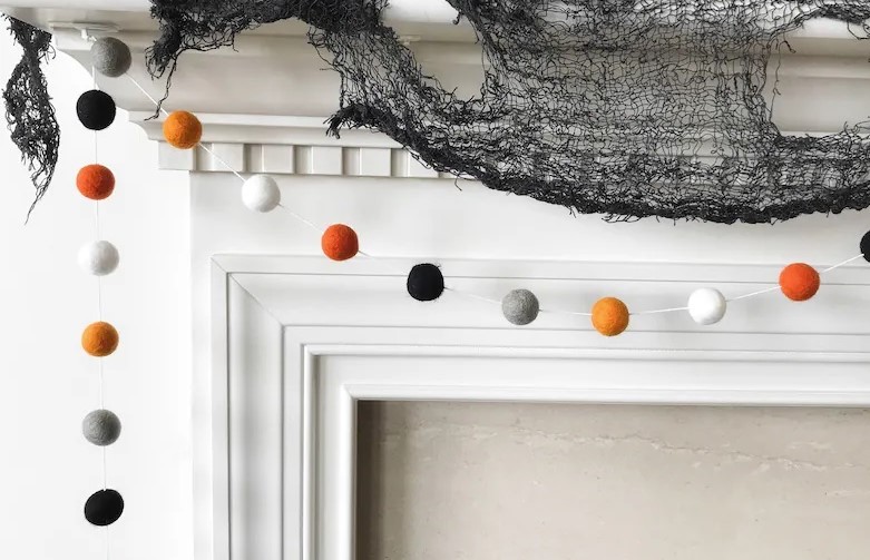 Anything that adds soft and subtle texture such as this felt ball Halloween garland shown in the photo (with felt balls in alternating colours of black, gray, burnt orange and white) make classy Halloween decorations