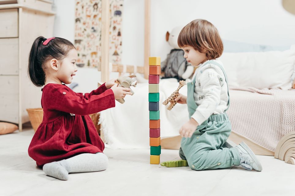 Two children stacking toy blocks