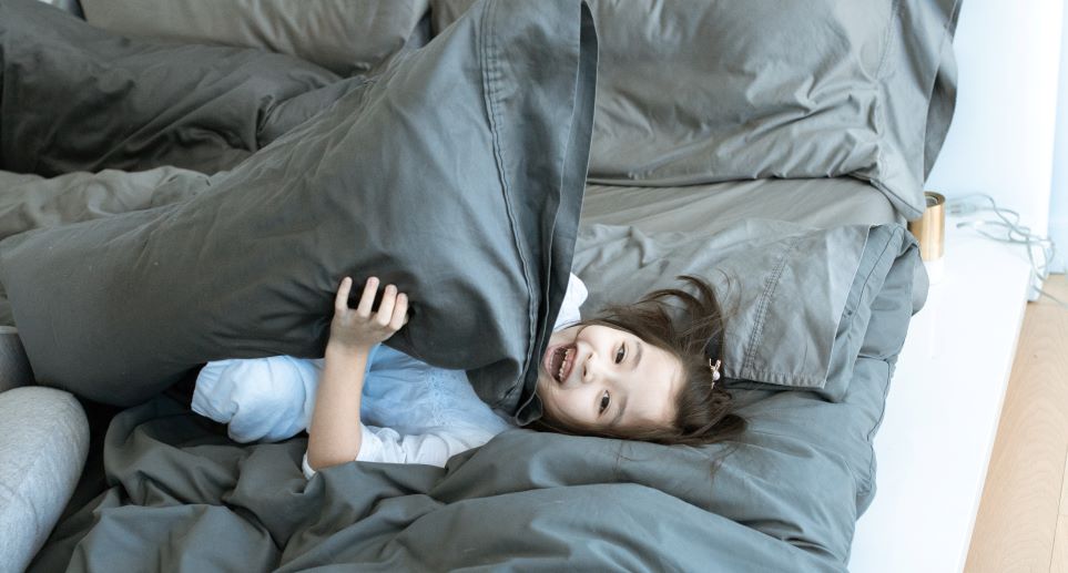 Young girl playing with pillow on mattress on floor
