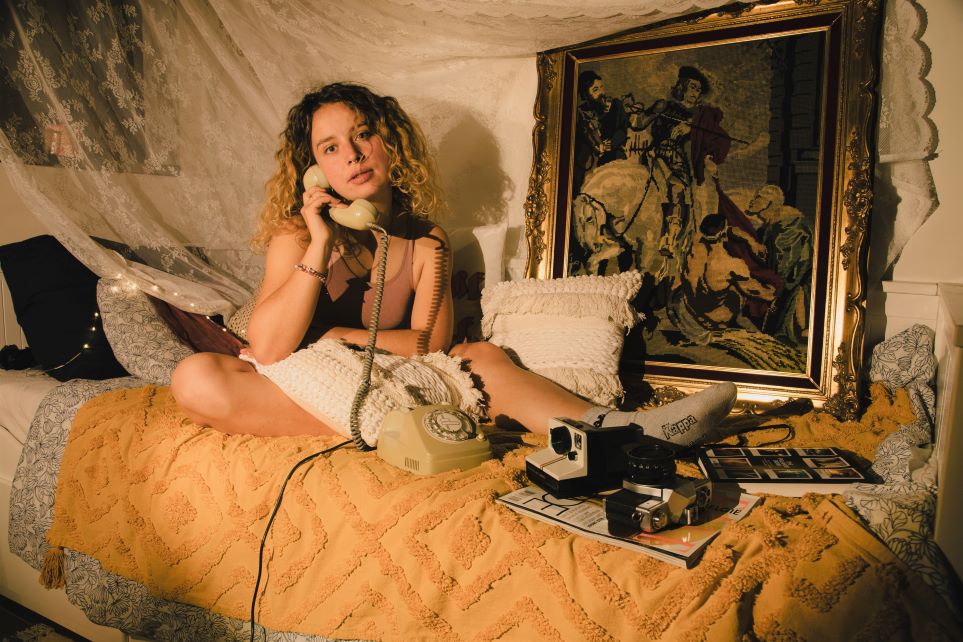 Cozy spot with telephone, magazine and twinkle lights in artsy bed