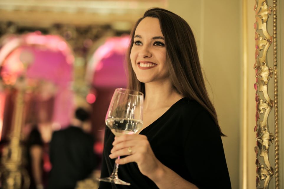 Woman smiling at upscale party, holding wine glass
