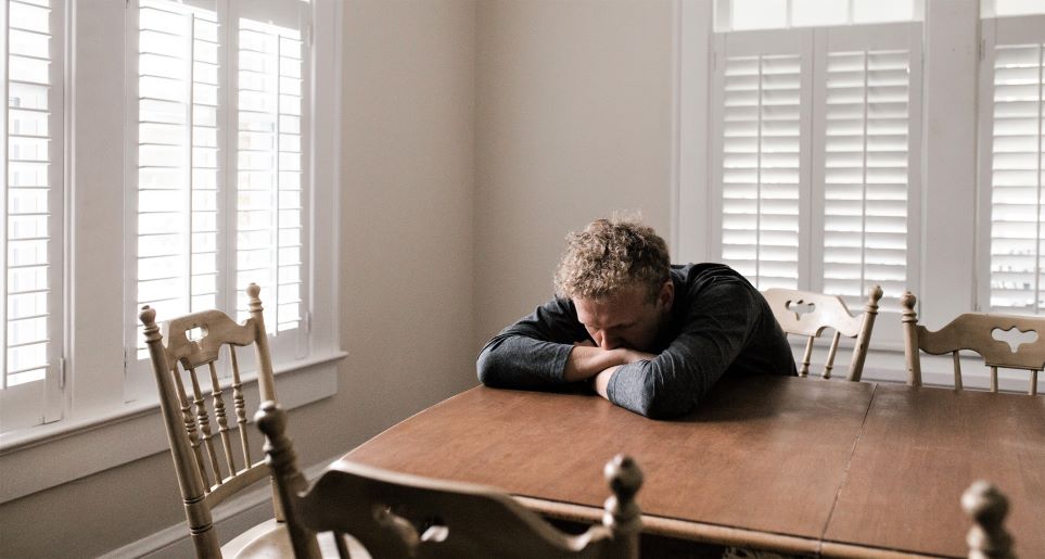 Man resting head on arms at table