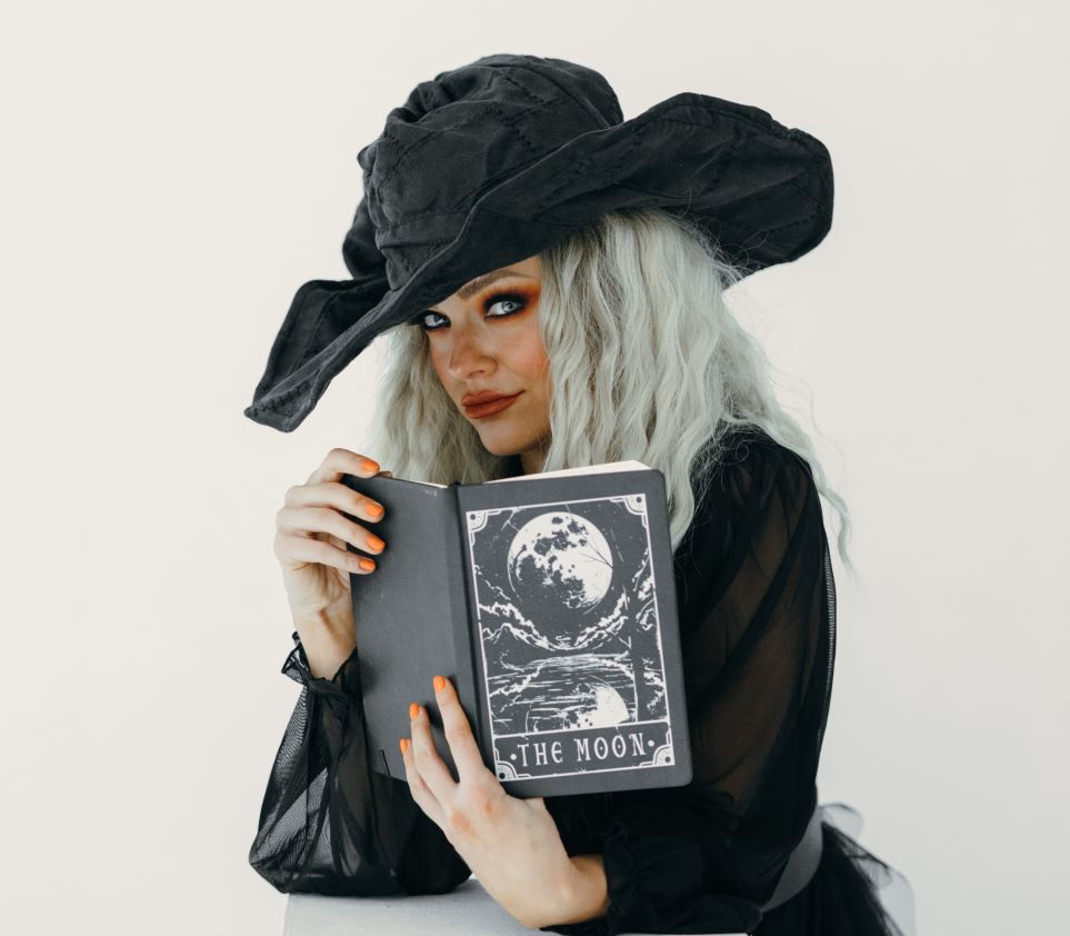 Woman dressed as witch, reading book about the moon