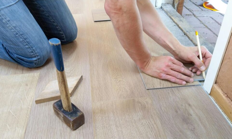 Close-up photo of person marking measurement at bottom of door frame while installing flooring