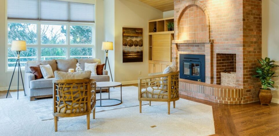 A pleasant living room with a couch and pillows and two cushioned chairs surrounding a coffee table, a couple of floor lamps for ambient lighting, area rugs, and a houseplant and wall hanging for an inviting space with a balanced stuff/space ratio