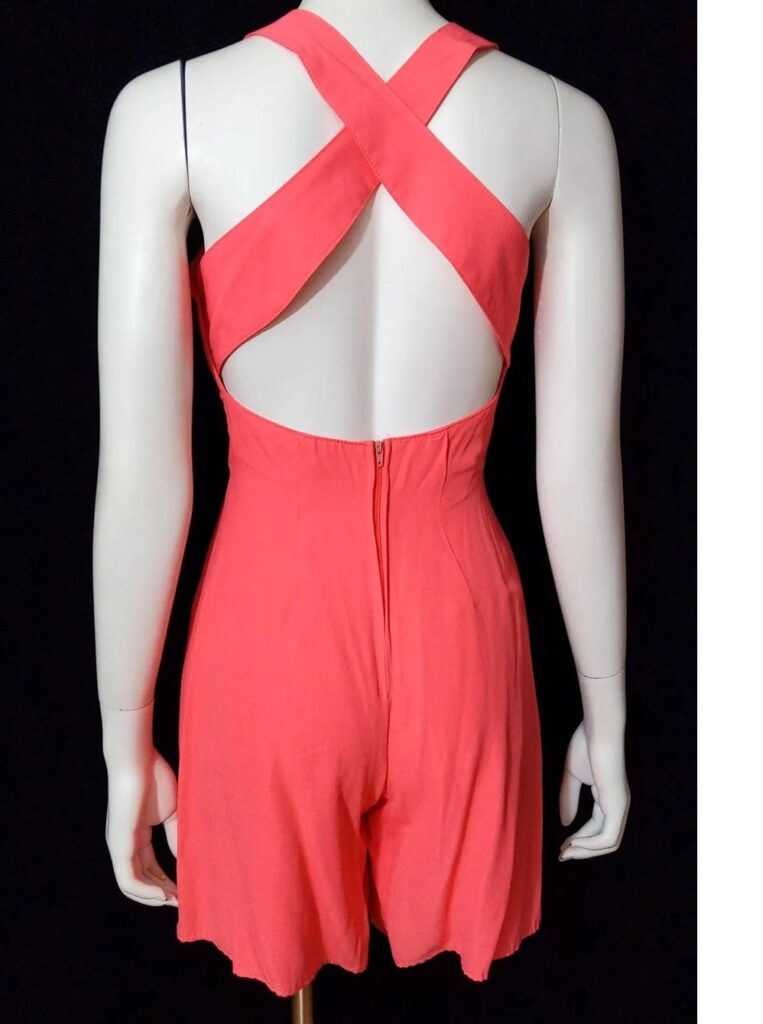 Photo of the back of a salmon-coloured mini romper with crisscross halter top, seen on mannequin