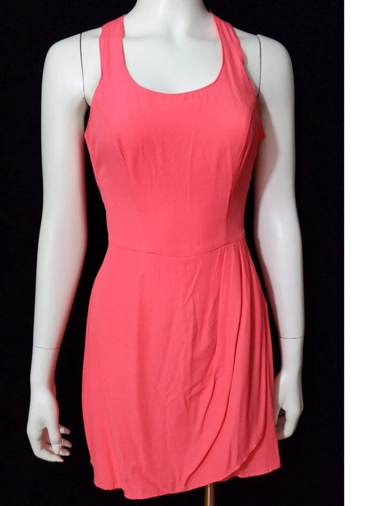 Photo of the front of a salmon-coloured mini romper skort with crisscross halter top, seen on mannequin