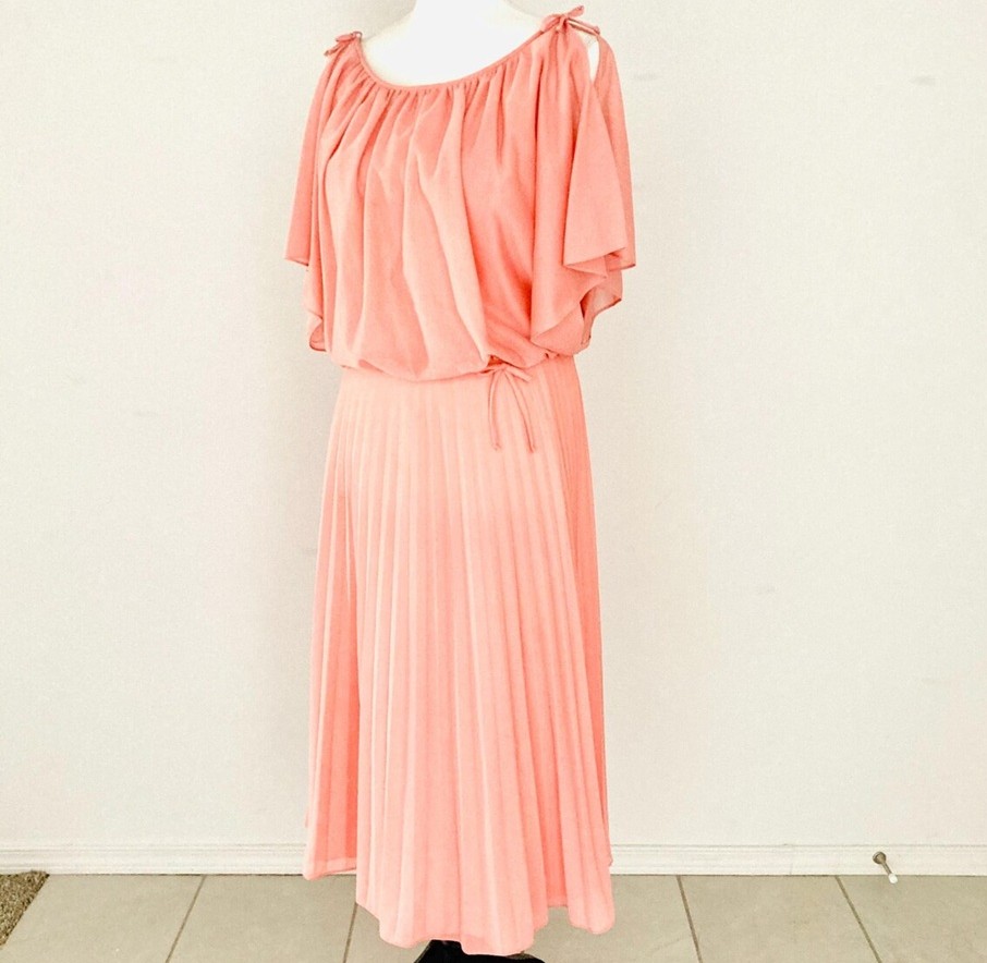 Photo of flowy vintage peach/salmon cocktail dress with pleated skirt on a mannequin