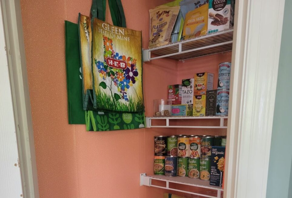 The upper portion of the open pantry stocked with organised dry goods and a few reusable grocery bags hanging from hook on wall. The walls are covered in a sparkling peach peel-and-stick wallpaper. Even if you can't outfit the walls of your kitchen and dining room with it, the pantry closet is a perfect opportunity to spruce up the space