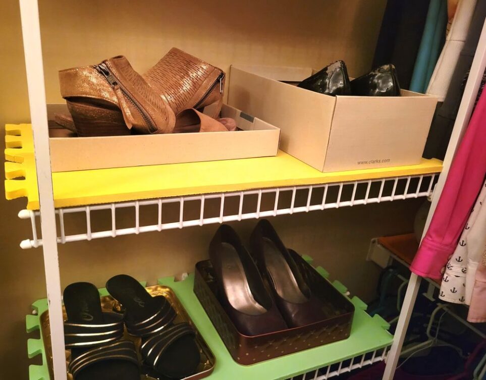 Close-up photo in primary closet of shelving with four pairs of shoes seen on two of the shelves, displayed in boxes and lids
