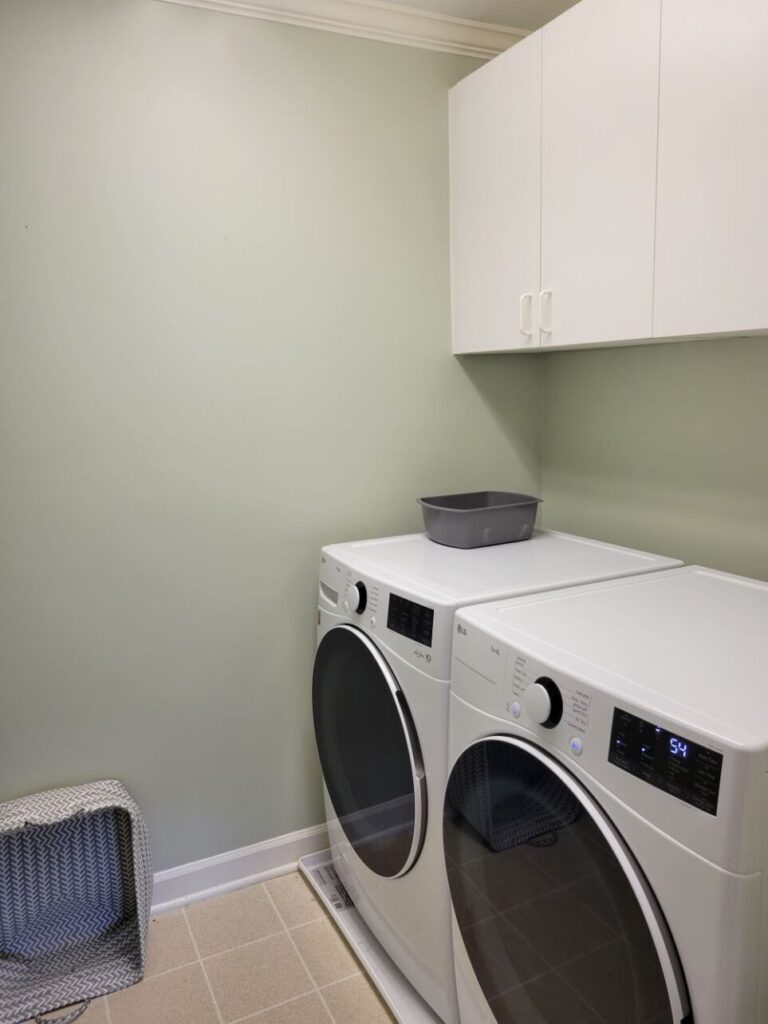 The washer and dryer in the laundry room with white cabinets above to store laundry detergent, stain remover, etc.