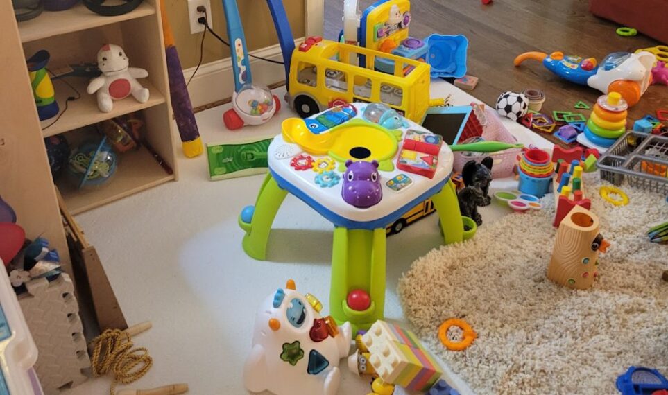 Close up photo of loads of toys scattered along floor in living room...purposefully kept out of the children's room!