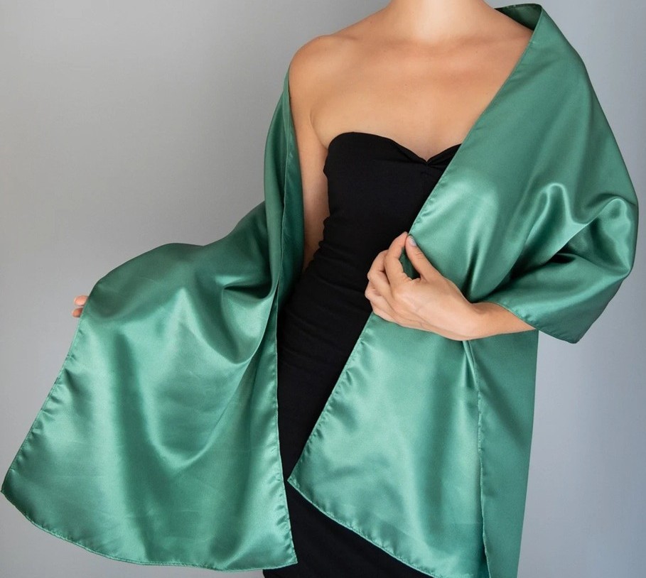 A model wears an emerald green satin shawl over a black dress