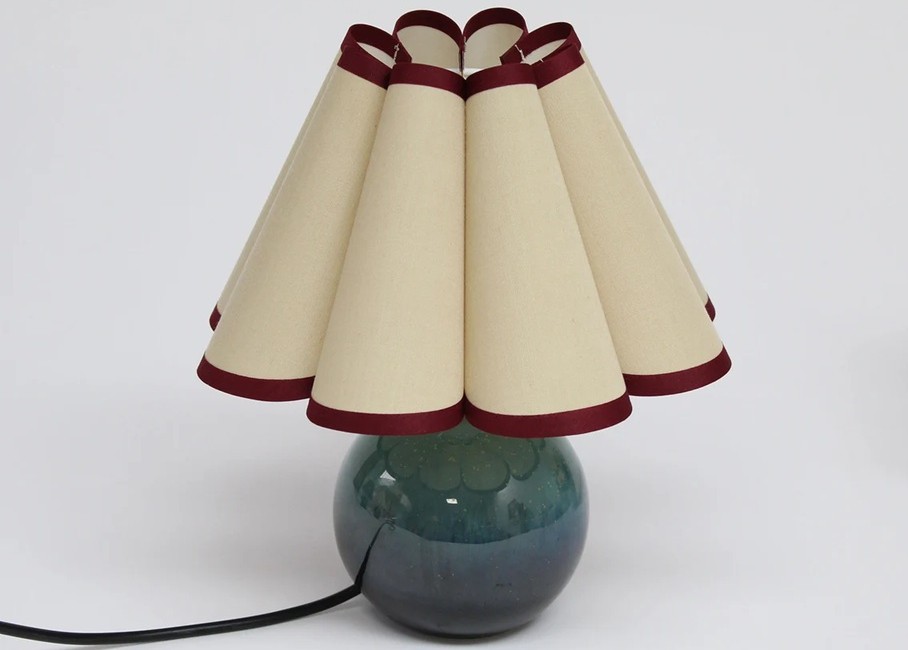 A small scalloped lampshade with jade green round porcelain base