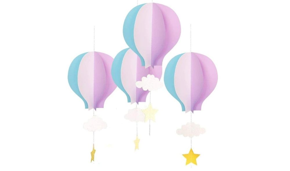 Blue and pink paper hot air balloons with white paper cloud cutouts and gold paper star cutouts hanging on the string below