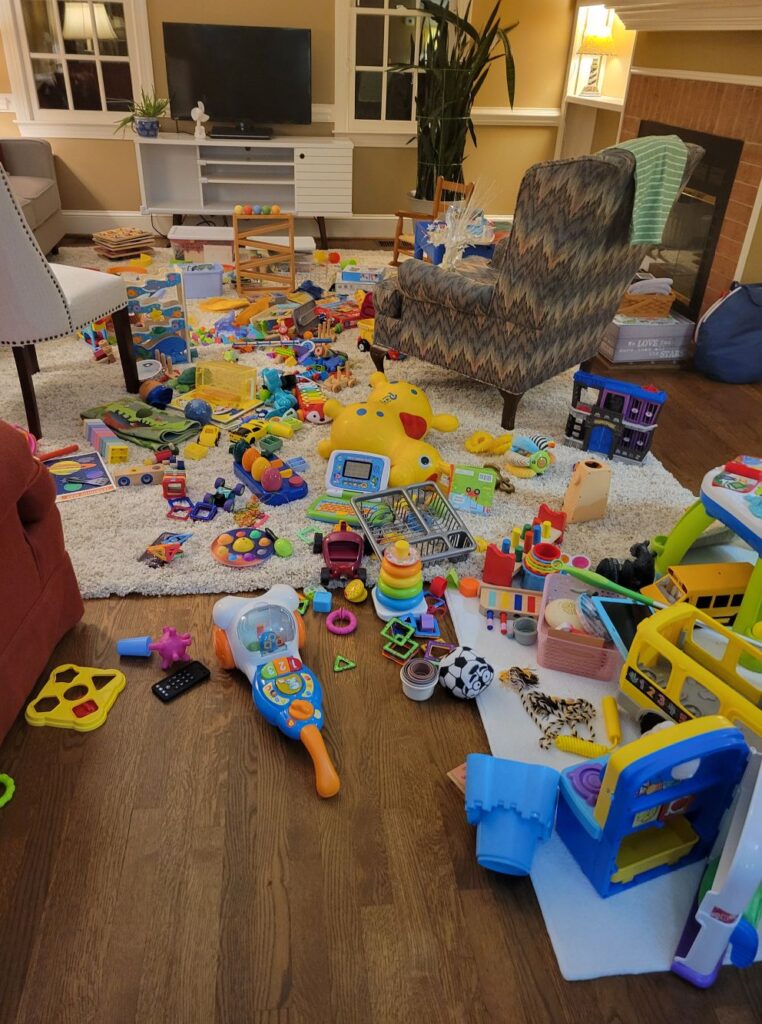 Many toys are strewn across the middle of a living room floor...a very happy and colourful sight, but terribly messy nonetheless! A toy display shelf is an excellent solution to corral most of the toys seen here