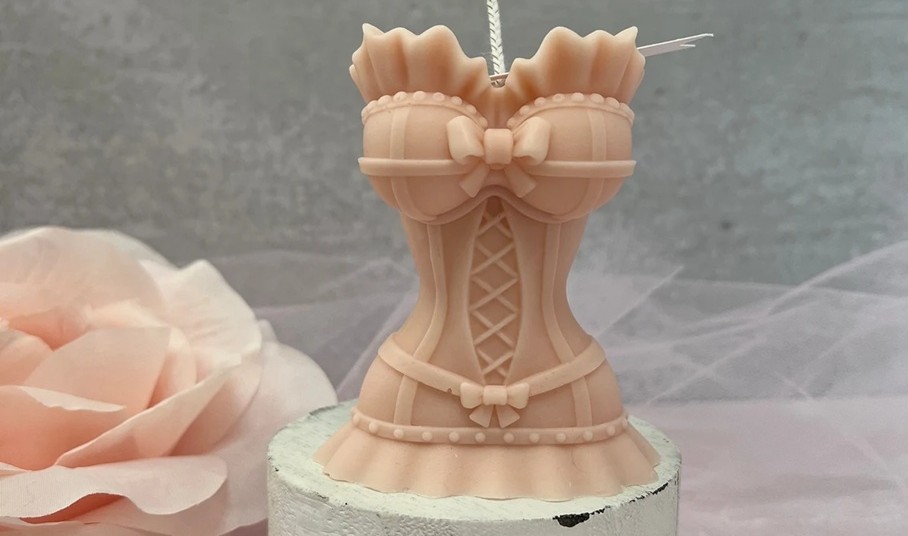 Close-up photo of an intricately shaped pale pink soy wax corset candle, a beautiful addition to an eccentric decor collection