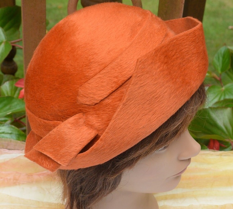 Close-up photo of an orange felt Schiaparelli hat on a mannequin head