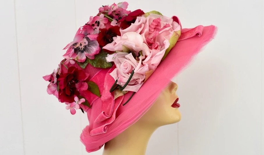 Close-up photo of a bright pink hat covered in faux flowers in various pink shades