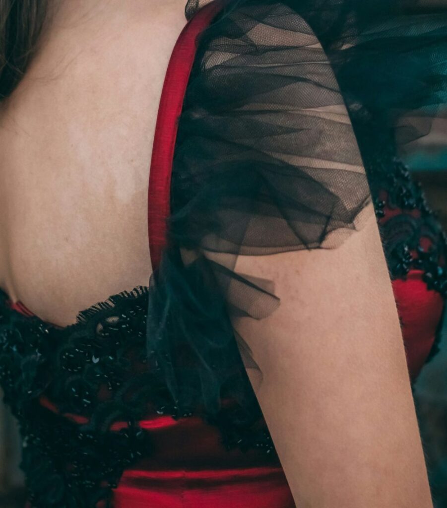 Babymetal-inspired classy Halloween costumes include tops like the one shown in this close-up photo of a woman wearing a bright red satin sleeveless top with black tulle detailing on the shoulders