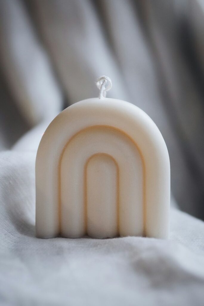 Close-up photo of a simple off-white rainbow-shaped clean burning candle made of soy wax
