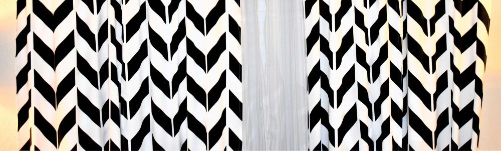 Close-up photo of a portion of two white-and-black chevron-striped curtains hanging on either side of a window