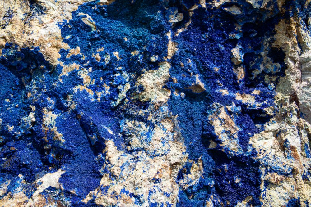 Close-up photo of streaks of bright blue lapis lazuli embedded in rock