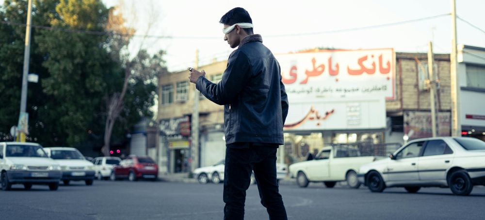 A blindfolded man navigating the street in Iran