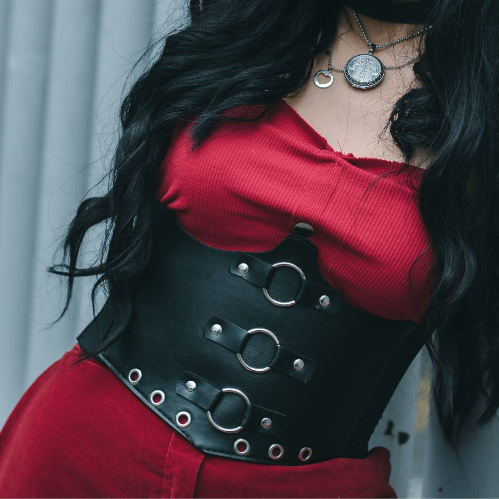 Close-up photo of a woman wearing a sleeveless red jumpsuit with a black leather boddice with silver metal rivets and rings, inspiring Babymetal-style classy Halloween costumes