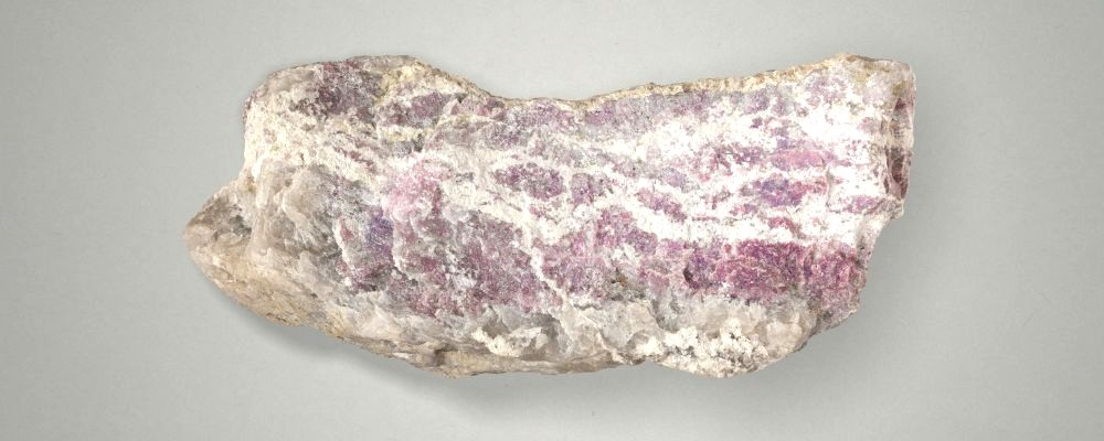 Close-up photo of raw Alvarrões Mine lepidolite mineral from Gonçalo, Guarda, Portugal. With lavender crystal mineralization of lepidolite, intersected with feldspar and quartz.