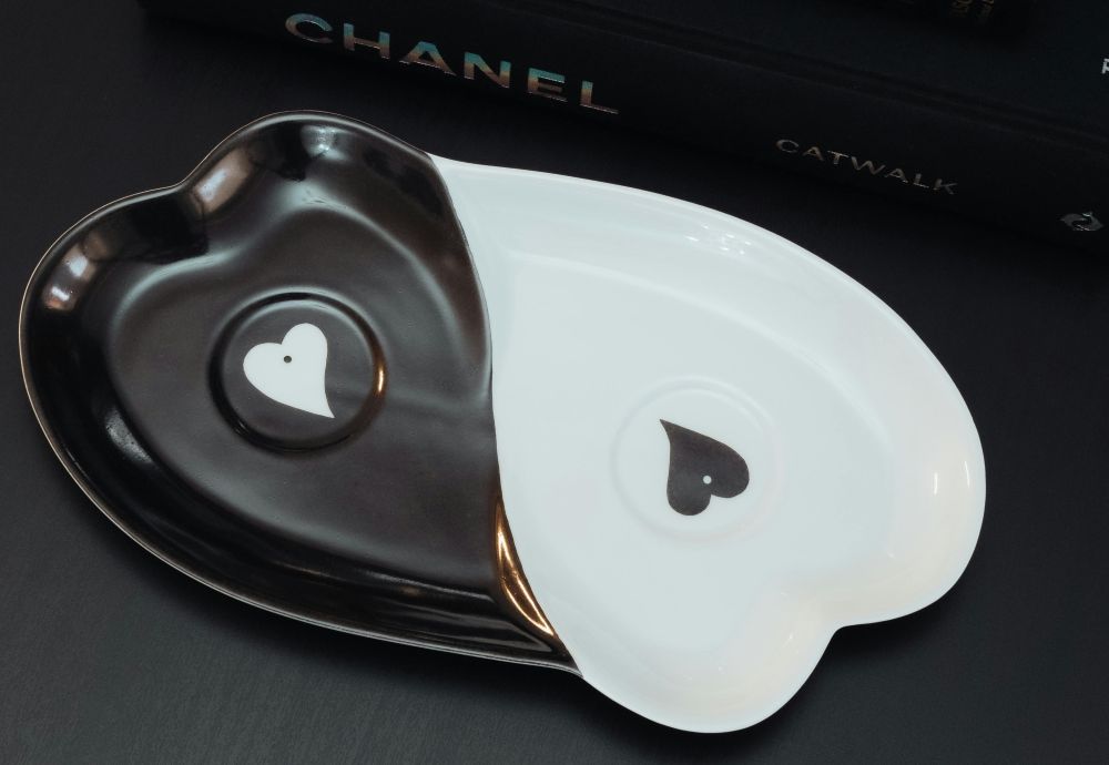Close-up photo of a tray in the shape of two oblong hearts making a ying-yang symbol, with heart dots in each center, in black and white