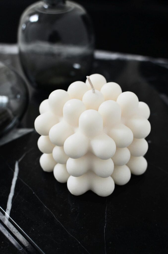 Close-up photo of a white textured cube candle atop a sleek black end table