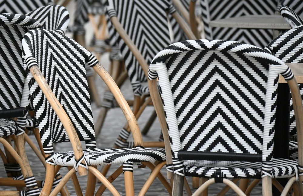 A cluster and black and white striped whicker chairs at an outdoor seating area outside a cafe