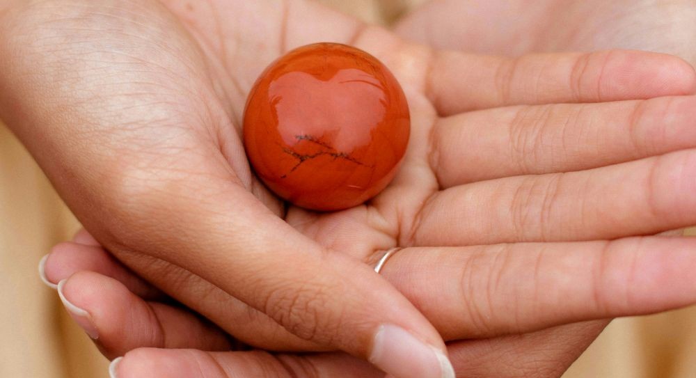 Close-up photo of a carnelian sphere in a woman's open palm