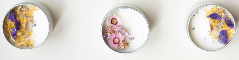 Soy candles are the most common clean burning candles. These ones shown in the photo (top-down, close-up) are poured in small metal tins with beautiful tiny dried flowers and herbs in pink, purple and yellow on top, surrounding wood wicks