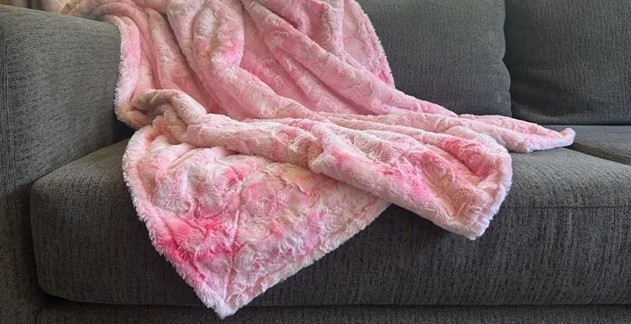 Faux fur 'minky' pink throw blanket draped over a gray couch