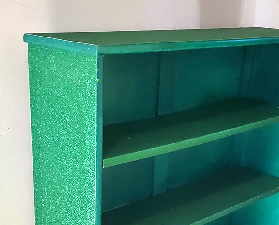Close up photo of party of a small bookcase that's been covered in sparkling green glitter peel and stick wallpaper