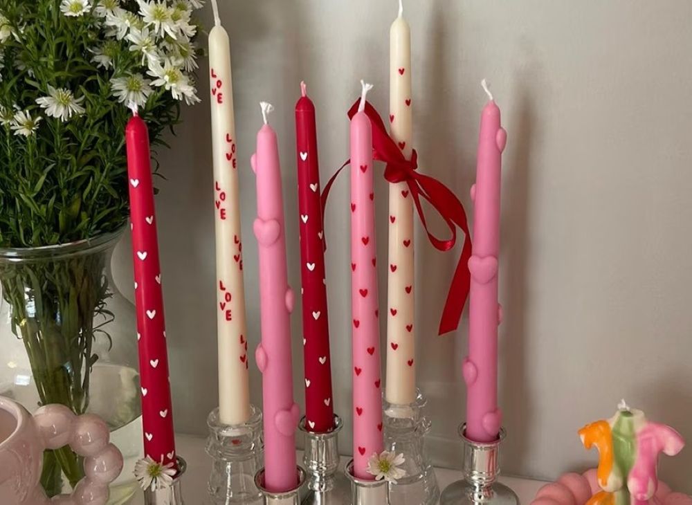 Lovecore-themed taper candles in red, cream and pink, with little hearts up the length and, in one candle, the word 'LOVE'