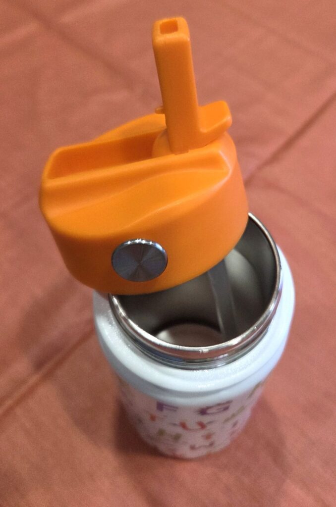 Children's stainless steel water bottle seen from above with its orange lid unscrewed and resting on the top, with the plastic straw in view and top of the orange flip straw on the lid open