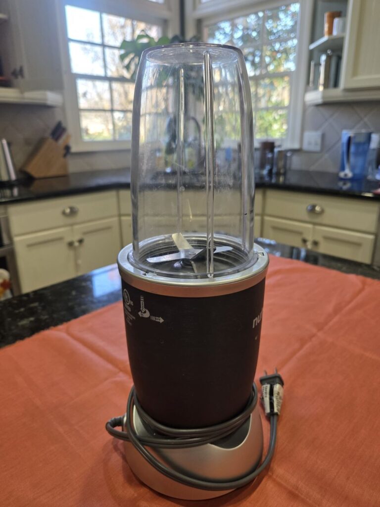 Household products that make it easy to maintain a healthy lifestyle, like this NutriBullet, are a definite win. Pictured is the NutriBullet base (with the cord wrapped around it/not plugged) and the clear plastic large-capacity smoothie cup upside-down on top, as it would appear while in use.