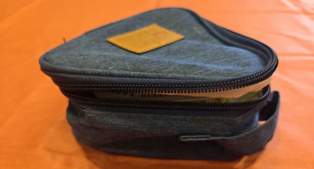 Close-up photo of a soft blue triangle-shaped insulated food storage container with a zipper lid