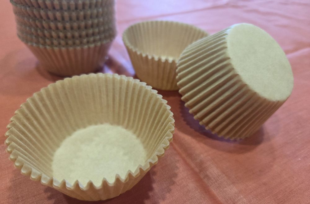 Close-up view of a stack of natural/dye-free cupcake liners as well as a few loose ones