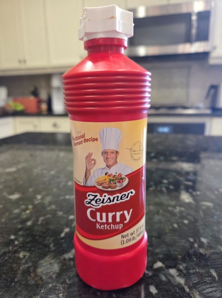 A red bottle of Ziesner brand curry ketchup atop a kitchen counter