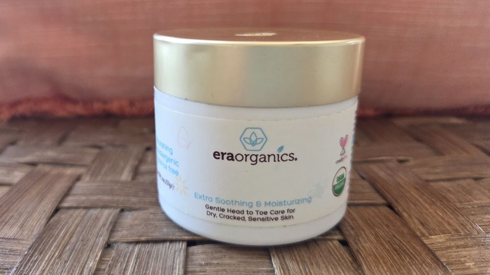 Close-up view of jar of Era Organics Extra Soothing & Moisturizing baby balm, as the label reads 'gentle head to toe care for dry, cracked, sensitive skin'