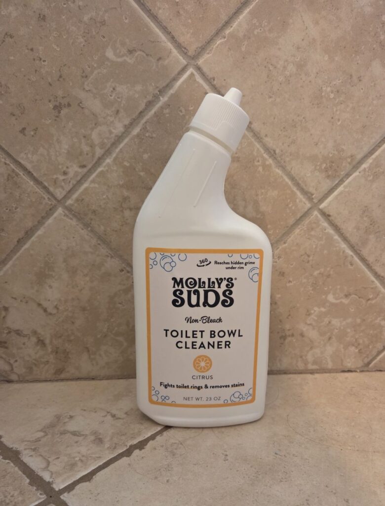 Bottle of Molly's Suds toilet bowl cleaner in front of tiled bathroom wall