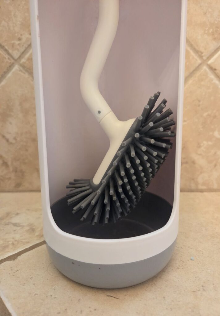 Close-up photo of silicone 'bristled' toilet brush hanging in touch-free stand (ends of bristles don't touch inner sides of stand)