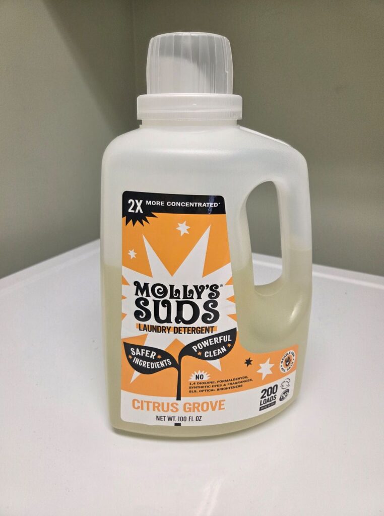 Bottle of Molly's Suds powder laundry detergent atop washing machine