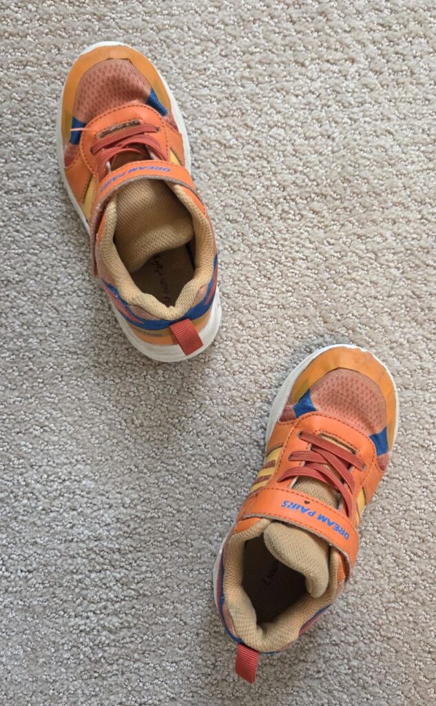 Top-down view of an orange pair of children's Dream Pairs athletic sneakers (with blue detailing) with Velcro straps and non-functional/decorative laces